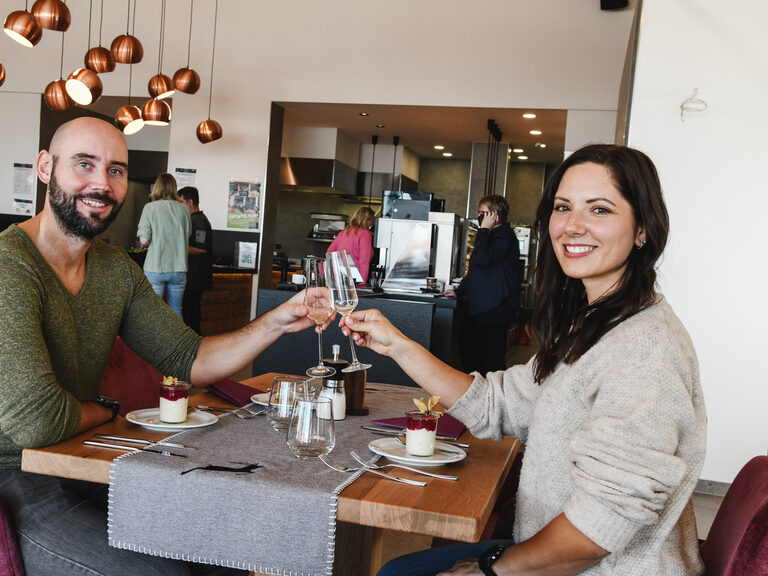 Paar mit Sektgläsern im Restaurant "Edelwies Alm" an. Ein Paar stößt mit Sektgläsern im Restaurant "Edelwies Alm" in Neukirchen an.
