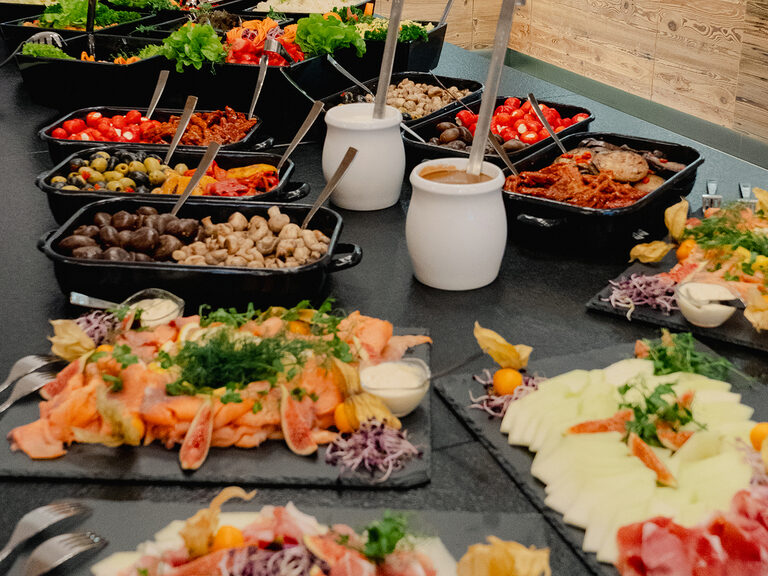 Verschiedene Platten im Restaurant "Edelwies Alm". Auf Platten ist eine große Auswahl aus Wurst und anderen Leckereien am Buffet aufgetischt.